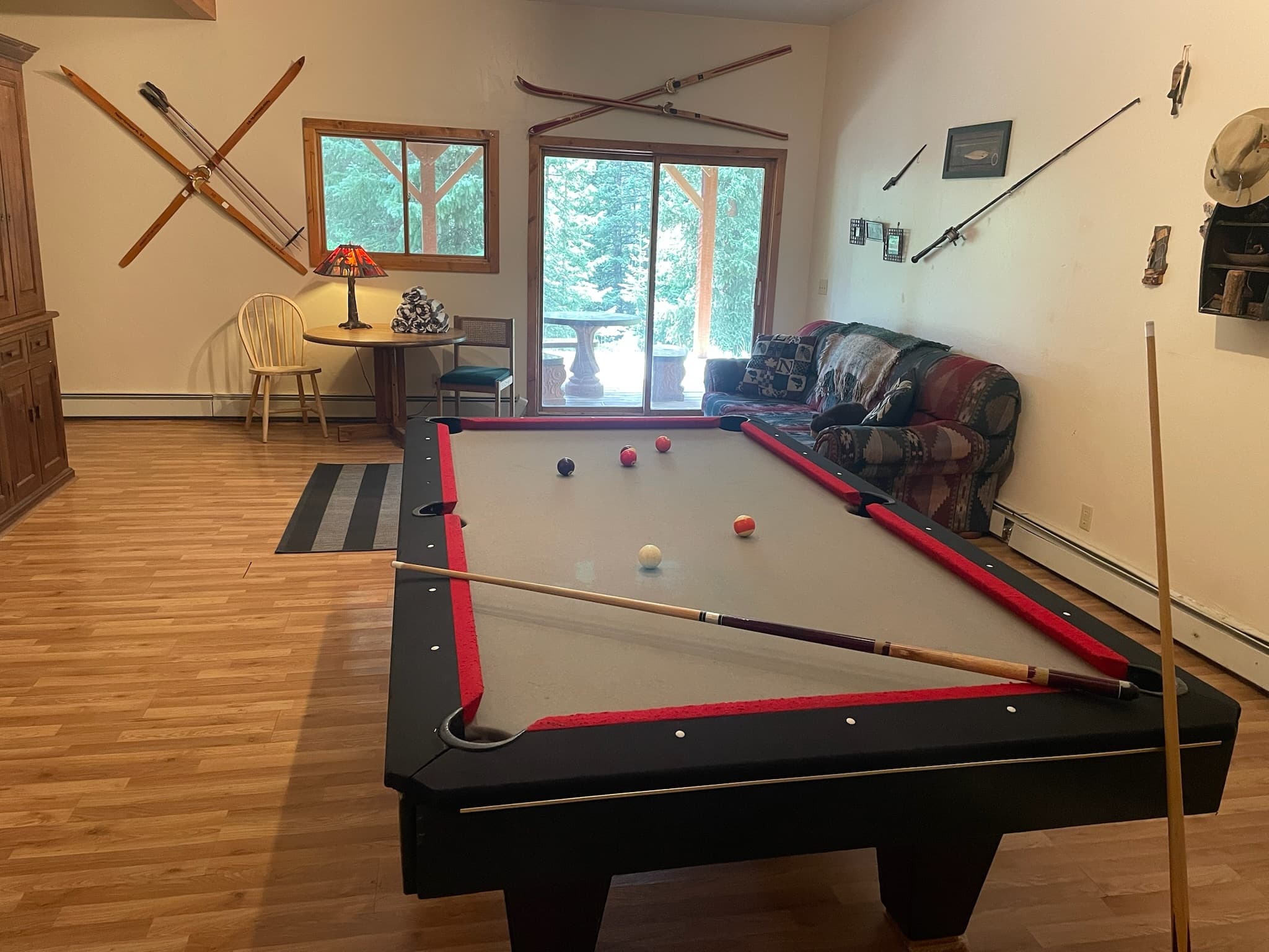 Grey felt pool table with red rails in a rustic room with vintage wooden skis.